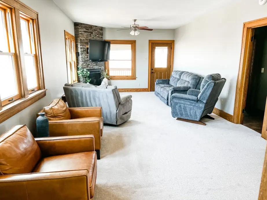 Living room with new light carpet and a stone fireplace, installed by Christian's Carpets
