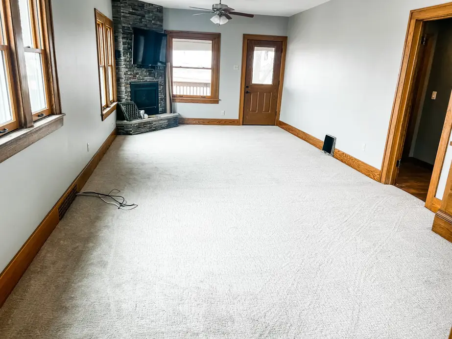 Carpeted living room with a stone fireplace wall, installation in progress