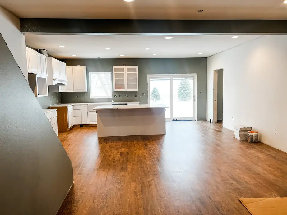 Open kitchen and living area with warm oak LVP flooring mid-install