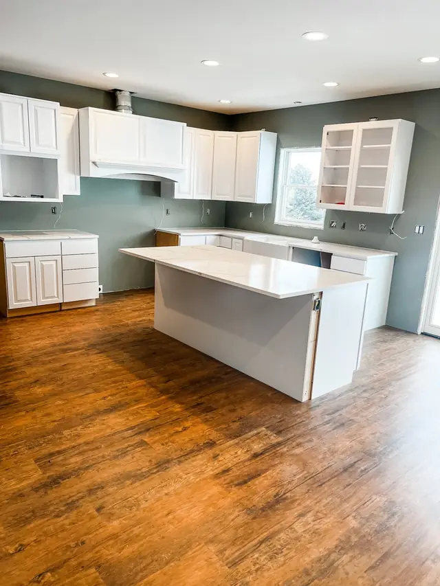 Kitchen with a white quartz island and warm oak luxury vinyl plank flooring