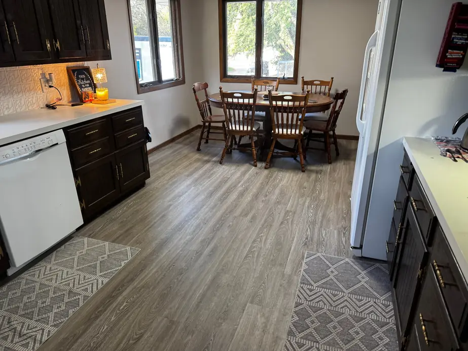 Dining nook with grey-toned LVP flooring and area rugs